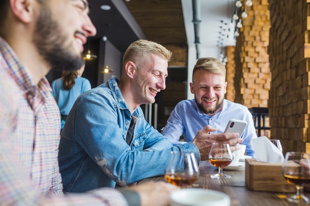 Equipaggi la mostra che si siede nel ristorante che mostra il telefono cellulare al suo amico