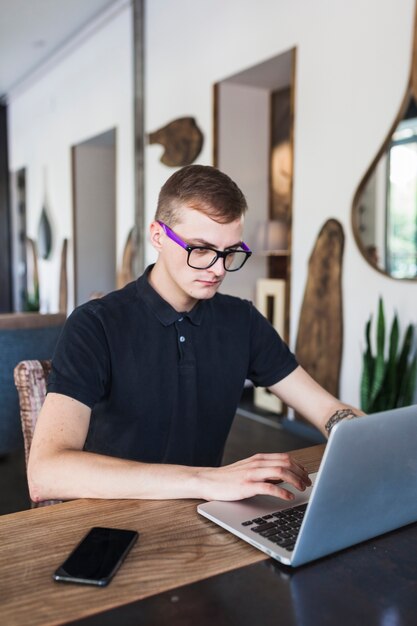 Equipaggi la seduta con il computer portatile in caffè