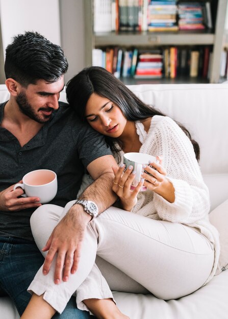 Equipaggi la seduta con la sua amica che tiene le tazze di caffè a disposizione