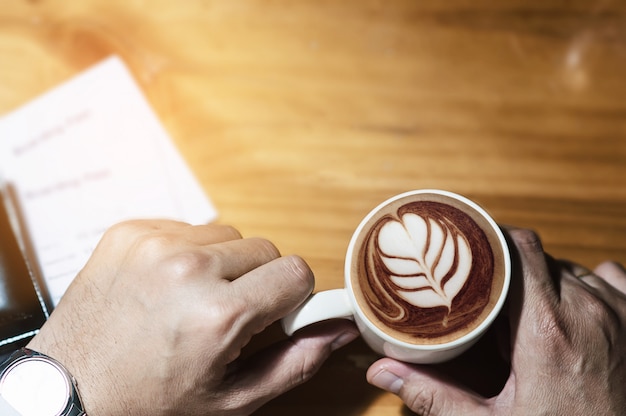 Equipaggi la tazza di caffè della tenuta e la carta d&#39;imbarco che aspettano il volo di viaggio in aeroplano