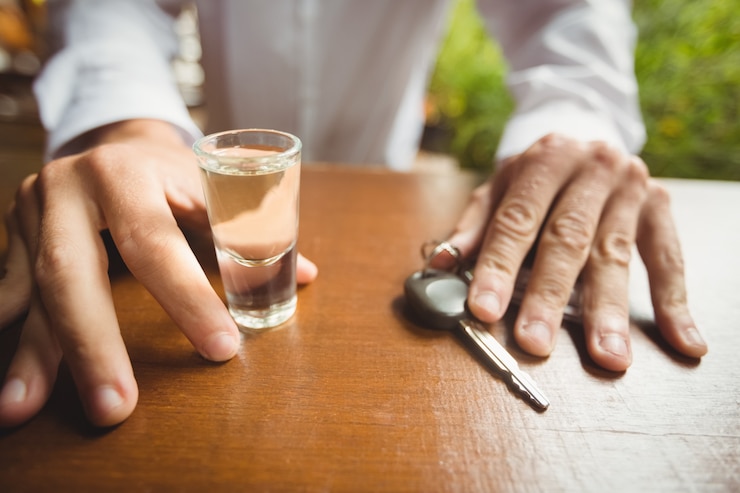 Foto gratuito equipaggi la tenuta del vetro del colpo di tequila e l'automobile digita il contatore della barra