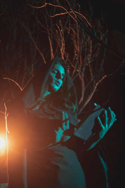 Equipaggi la tenuta della lanterna e un libro nella notte