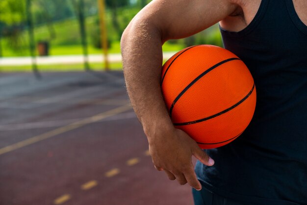 Equipaggi la tenuta della palla sul primo piano del campo da pallacanestro