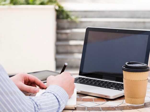 Equipaggi lavorare al computer portatile fuori mentre mangiano il caffè