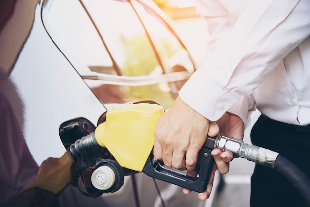 Equipaggi mettere il combustibile della benzina nella sua automobile in una stazione di servizio della pompa