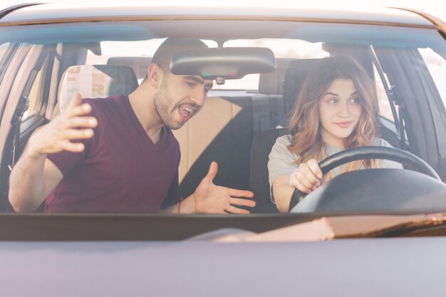 Esame di guida. L'istruttore maschio insegna all'auto femminile inesperta dell'azionamento dell'apprendista