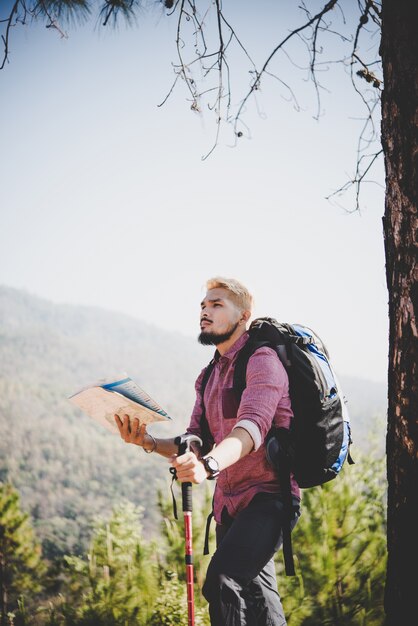 Escursionista con mappa e grande zaino da viaggio che viaggiano verso la montagna.