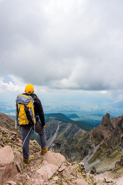 Escursionista con uno zaino in piedi sulla cima della montagna