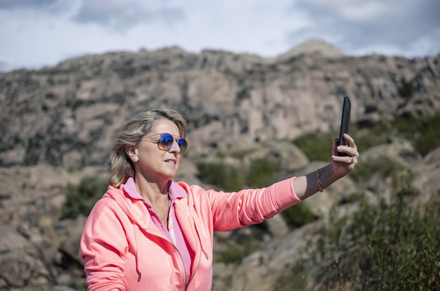 Escursionista femminile che utilizza il suo telefono e scatta foto della splendida vista