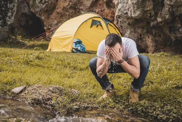 Escursionista lavando il suo volto nel fiume