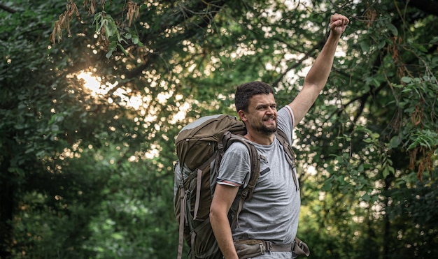 Escursionista su un'escursione con un grande zaino su uno sfondo sfocato della foresta.