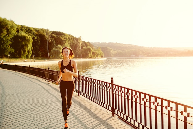 Esecuzione di donna. Runner jogging in pieno sole. Addestramento femminile del modello di forma fisica fuori nel parco