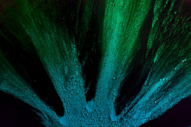 Esplosione di polvere blu e verde su sfondo nero