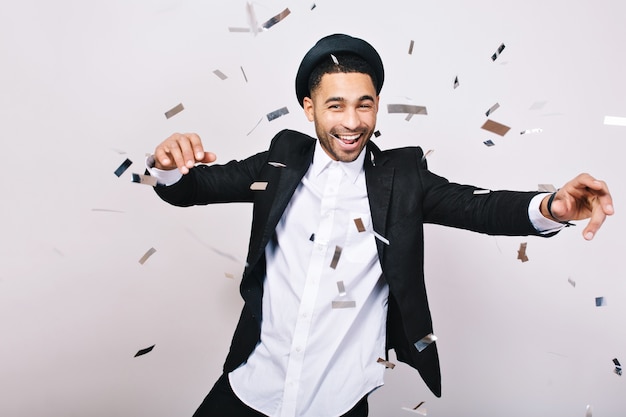 Esprimendo vivaci emozioni positive del bel ragazzo in cappello, vestito che si diverte in orpelli. Celebrare una grande festa, tempo libero, fine settimana, buon umore, sorridere.