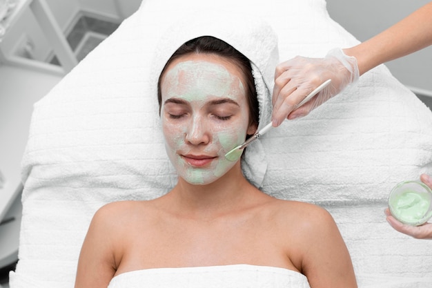 Estetista che applica maschera facciale su cliente femminile