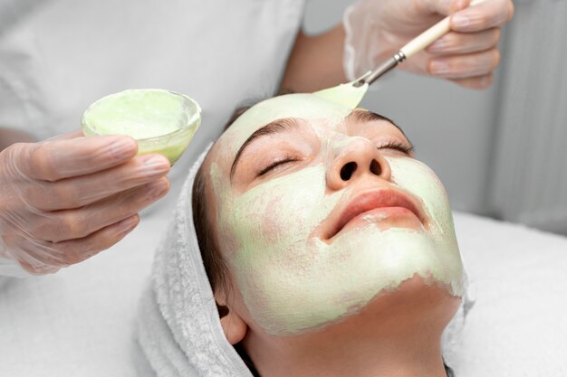 Estetista che applica maschera facciale su cliente femminile