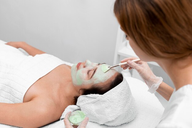 Estetista che applica maschera facciale sul cliente femminile