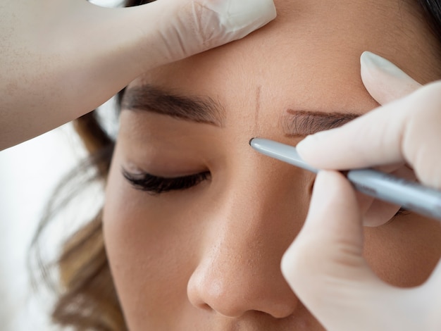 Estetista che esegue un trattamento di microblading sulle sopracciglia di una cliente