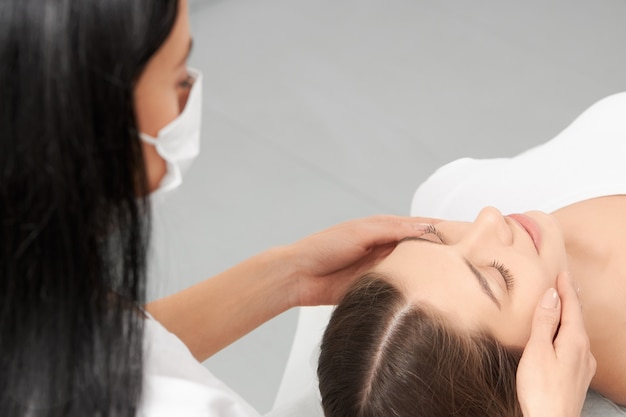 Estetista che fa massaggio per il viso con cosmetici