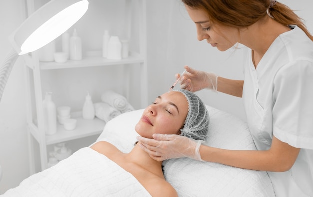 Estetista che fa riempitivo dell'iniezione sul cliente femminile al salone