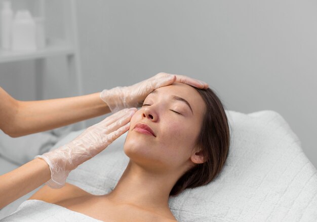 Estetista con una cliente femminile al salone per la routine di cura del viso