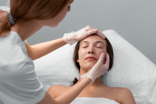 Estetista con una cliente femminile al salone per la routine di cura del viso
