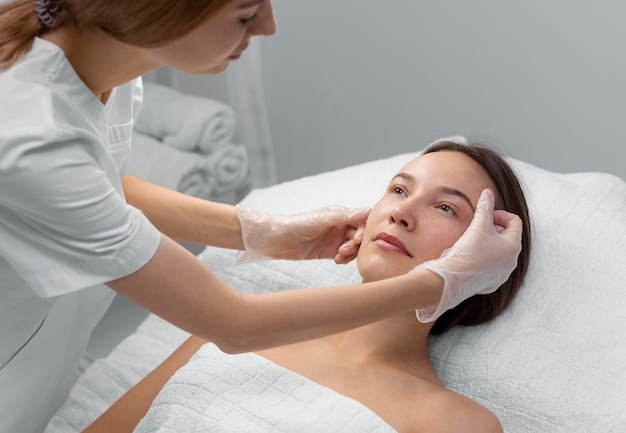Estetista con una cliente femminile al salone per la routine di cura del viso