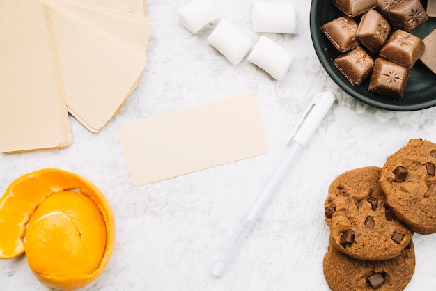 Etichetta vuota con pezzi di cioccolato; marshmallow; penna; biscotti e scorza d&#39;arancia