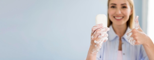 Faccina di sapone della holding della donna di smiley e dare pollici in su