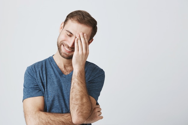 Facepalm sorridente dell'uomo dopo lo scherzo imbarazzante