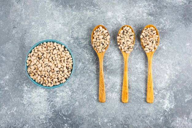 Fagioli bianchi in ciotola blu e cucchiai di legno.