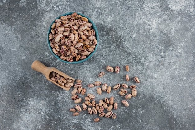 Fagioli crudi e cucchiaio di legno su marmo.