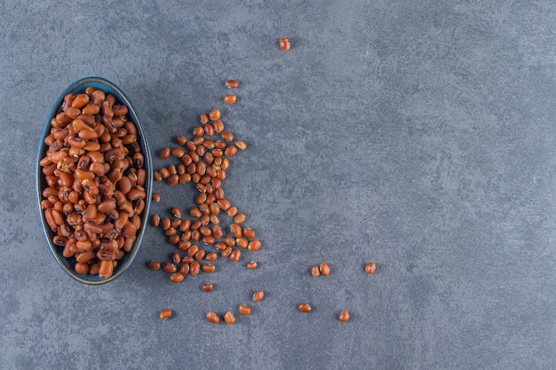 Fagioli crudi in una ciotola sulla superficie blu