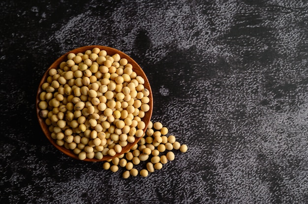 Fagioli gialli in una ciotola di legno sul pavimento di cemento nero.