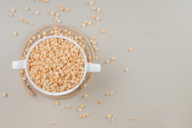 Fagioli gialli in una tazza di ceramica su cemento.