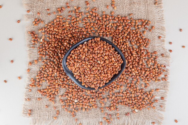 Fagioli marroni in un piatto di ceramica su cemento.