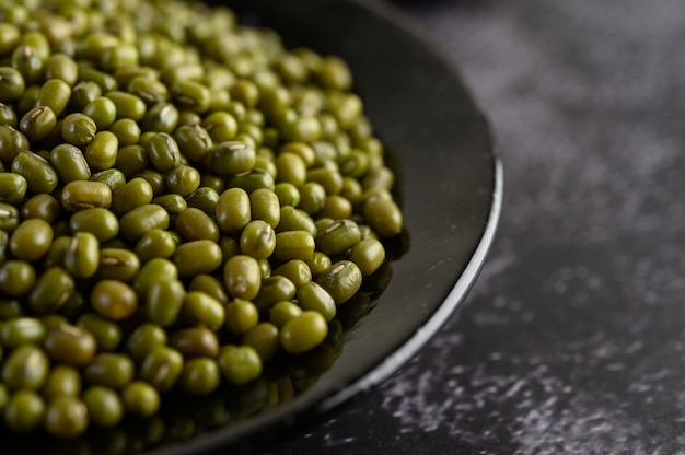 Fagioli verdi sul piatto sul pavimento di cemento nero.