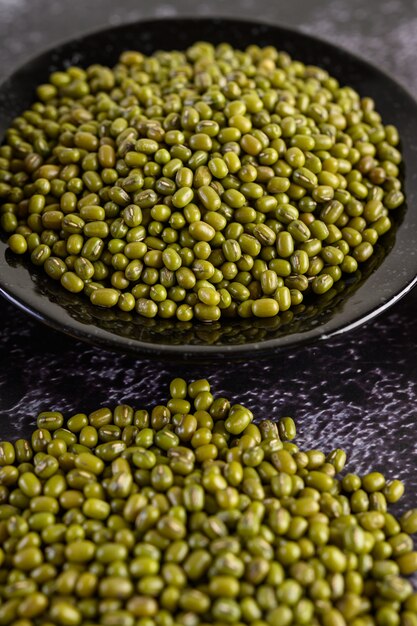 Fagioli verdi sul piatto sul pavimento di cemento nero.