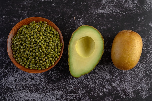 Fagiolo verde, avocado e kiwi su un pavimento di cemento nero.