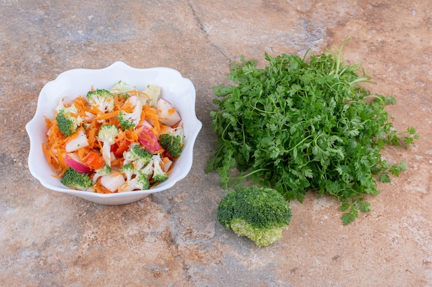 Fagottino di coriandolo, broccoli e piatto di insalata mista di verdure esposte sulla superficie in marmo