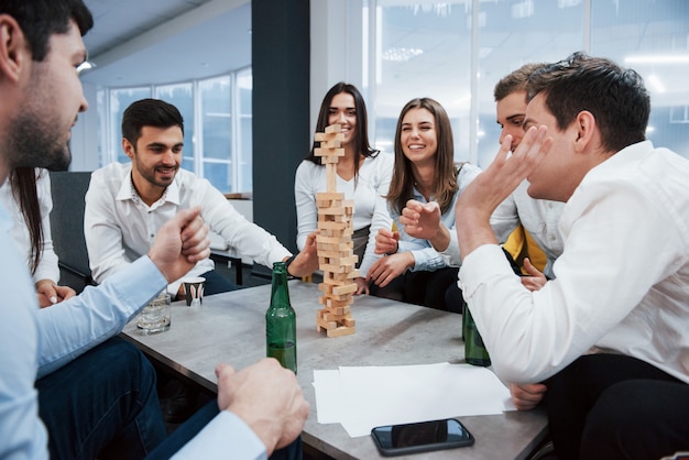 Fai attenzione per favore. Festeggiamo un affare di successo. Giovani impiegati seduti vicino al tavolo con l'alcol