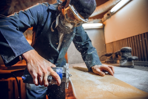 Falegname con sega circolare per il taglio di assi di legno. Dettagli costruttivi del lavoratore di sesso maschile o uomo a portata di mano con utensili elettrici