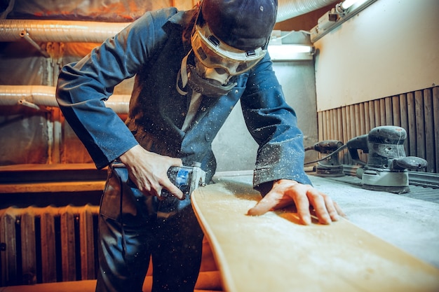 Falegname con sega circolare per il taglio di assi di legno. Dettagli costruttivi del lavoratore di sesso maschile o uomo a portata di mano con utensili elettrici