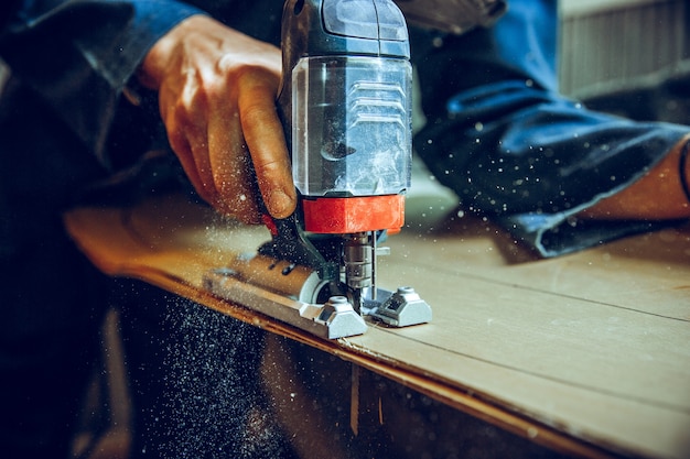 Falegname con sega circolare per il taglio di assi di legno. Dettagli costruttivi del lavoratore maschio o uomo pratico con utensili elettrici