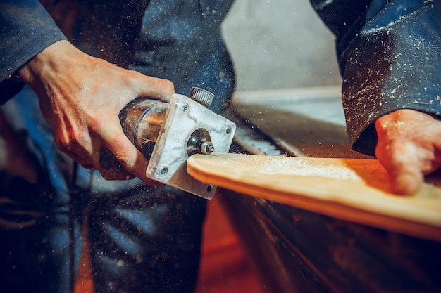 Falegname con sega circolare per il taglio di assi di legno. Dettagli costruttivi del lavoratore maschio o uomo pratico con utensili elettrici