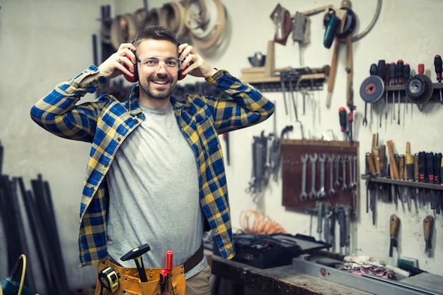 Falegname in officina che indossa la protezione per le orecchie e si prepara per il lavoro