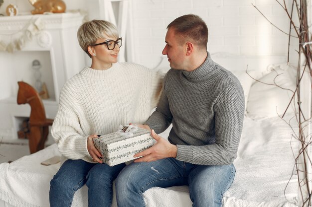 Famiglia a casa. Coppia vicino a decorazioni natalizie. Donna in un maglione grigio.