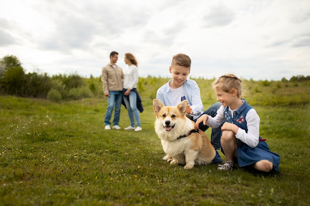 Famiglia a tutto campo che gioca con il cane all'aperto