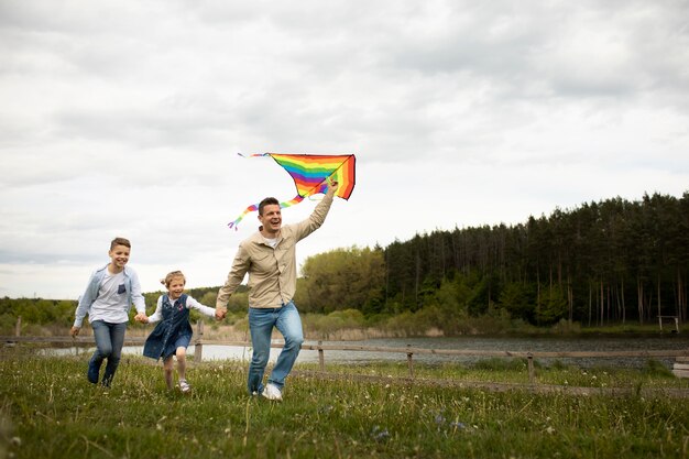 Famiglia a tutto campo con aquilone arcobaleno