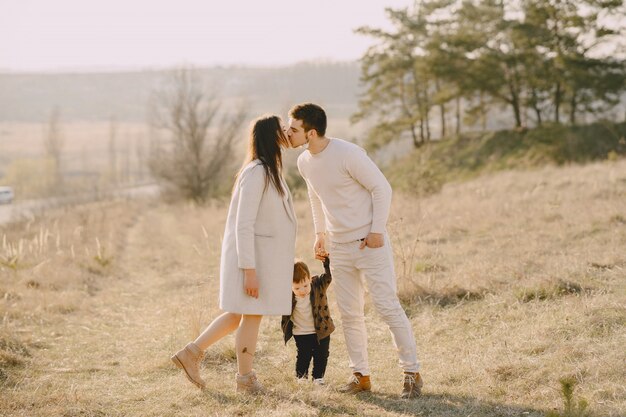 Famiglia alla moda che cammina su un campo soleggiato